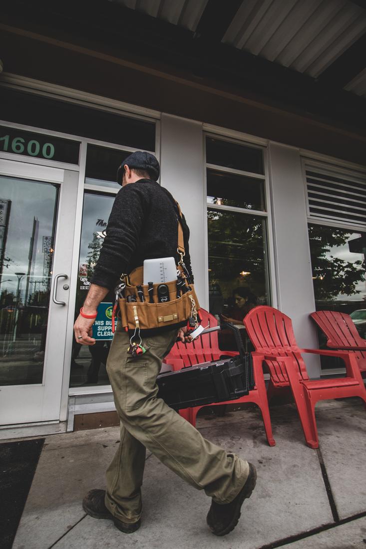A technician carrying his tool bag and kit into a local café