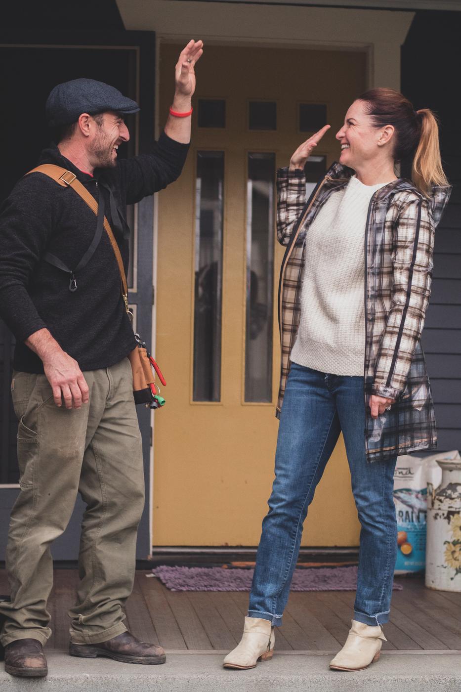 A Sage Conservation technician and a homeowner share a high-five on her front porch after a Tune-Up