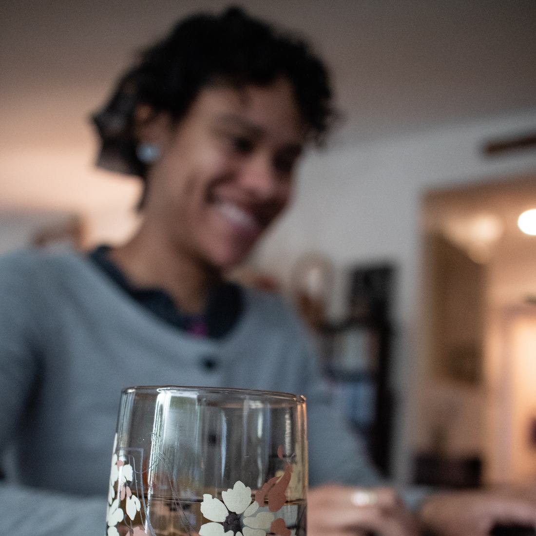 A smiling homeowner, softly out of focus behind a glass of water